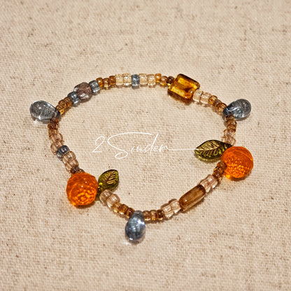 This is a bracelet made of Czech beads, orange slice spacers, leaf spacers, blue teardrop accents and elastic cord. The beads’ crystal-clear translucency catches light like dewdrops—perfect for adding a luxe touch to everyday outfits.