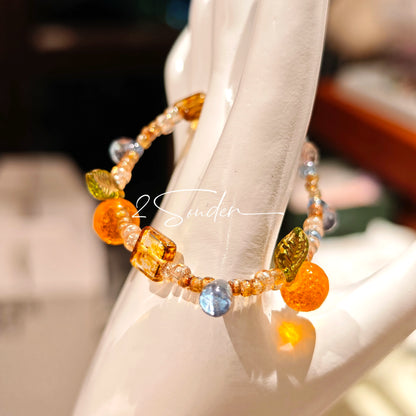 This is a bracelet made of Czech beads, orange slice spacers, leaf spacers, blue teardrop accents and elastic cord. The beads’ crystal-clear translucency catches light like dewdrops—perfect for adding a luxe touch to everyday outfits.