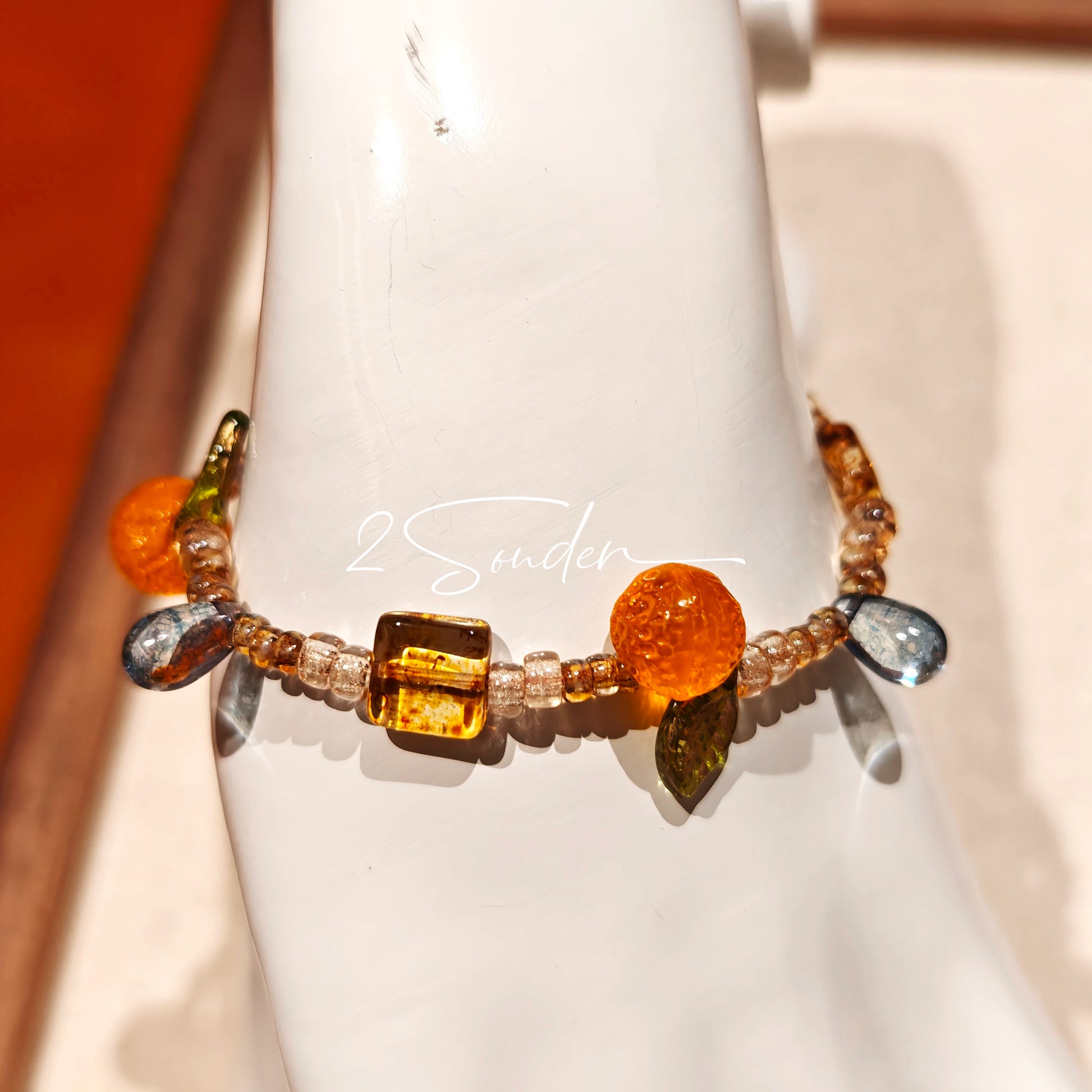This is a bracelet made of Czech beads, orange slice spacers, leaf spacers, blue teardrop accents and elastic cord. The beads’ crystal-clear translucency catches light like dewdrops—perfect for adding a luxe touch to everyday outfits.