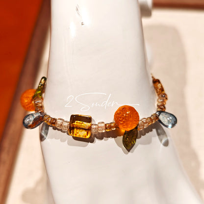 This is a bracelet made of Czech beads, orange slice spacers, leaf spacers, blue teardrop accents and elastic cord. The beads’ crystal-clear translucency catches light like dewdrops—perfect for adding a luxe touch to everyday outfits.