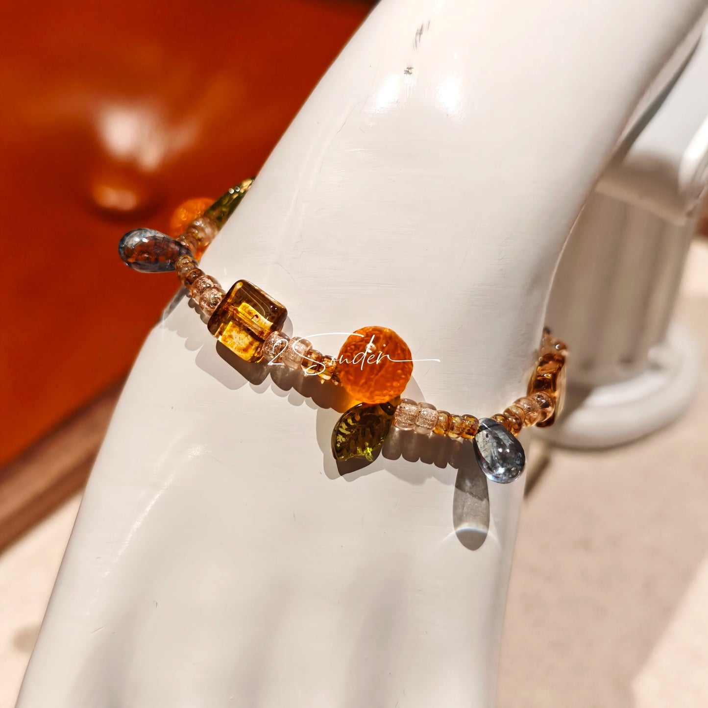 This is a bracelet made of Czech beads, orange slice spacers, leaf spacers, blue teardrop accents and elastic cord. The beads’ crystal-clear translucency catches light like dewdrops—perfect for adding a luxe touch to everyday outfits.