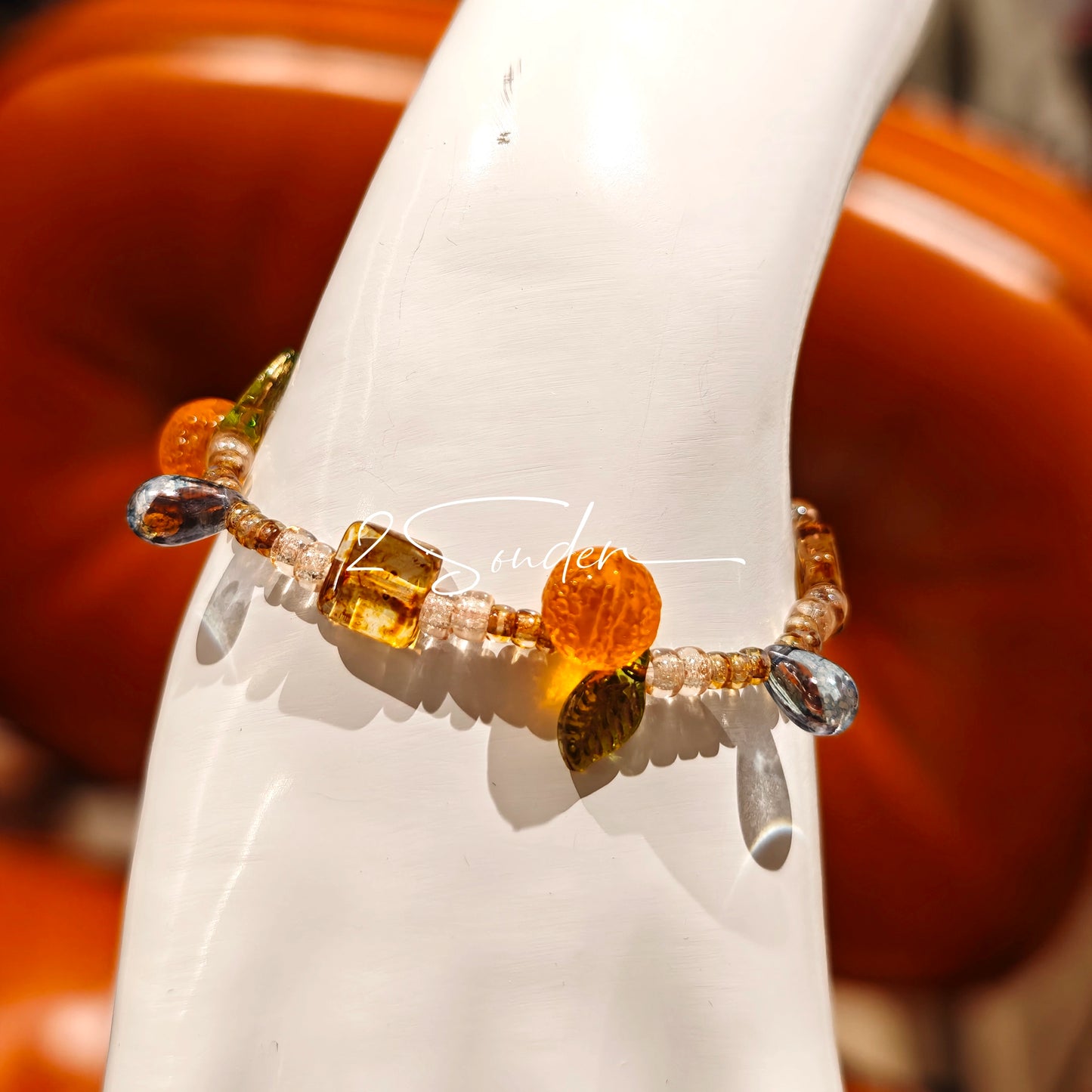 This is a bracelet made of Czech beads, orange slice spacers, leaf spacers, blue teardrop accents and elastic cord. The beads’ crystal-clear translucency catches light like dewdrops—perfect for adding a luxe touch to everyday outfits.