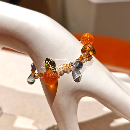 This is a bracelet made of Czech beads, orange slice spacers, leaf spacers, blue teardrop accents and elastic cord. The beads’ crystal-clear translucency catches light like dewdrops—perfect for adding a luxe touch to everyday outfits.