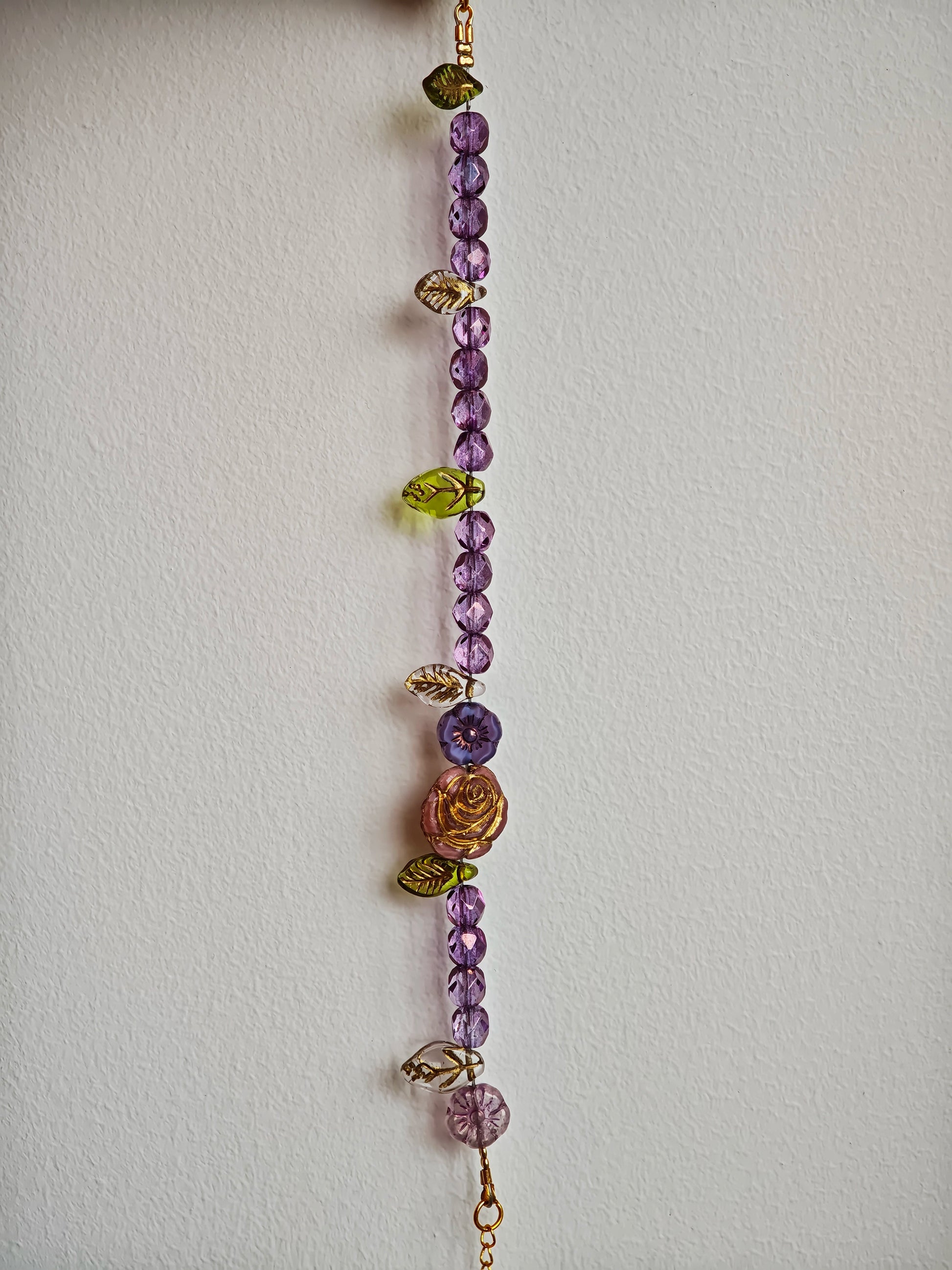 A purple hand-strung bracelet with luminous Czech glass beads & delicate botanical charms.