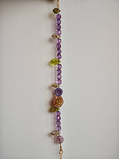 A purple hand-strung bracelet with luminous Czech glass beads & delicate botanical charms.