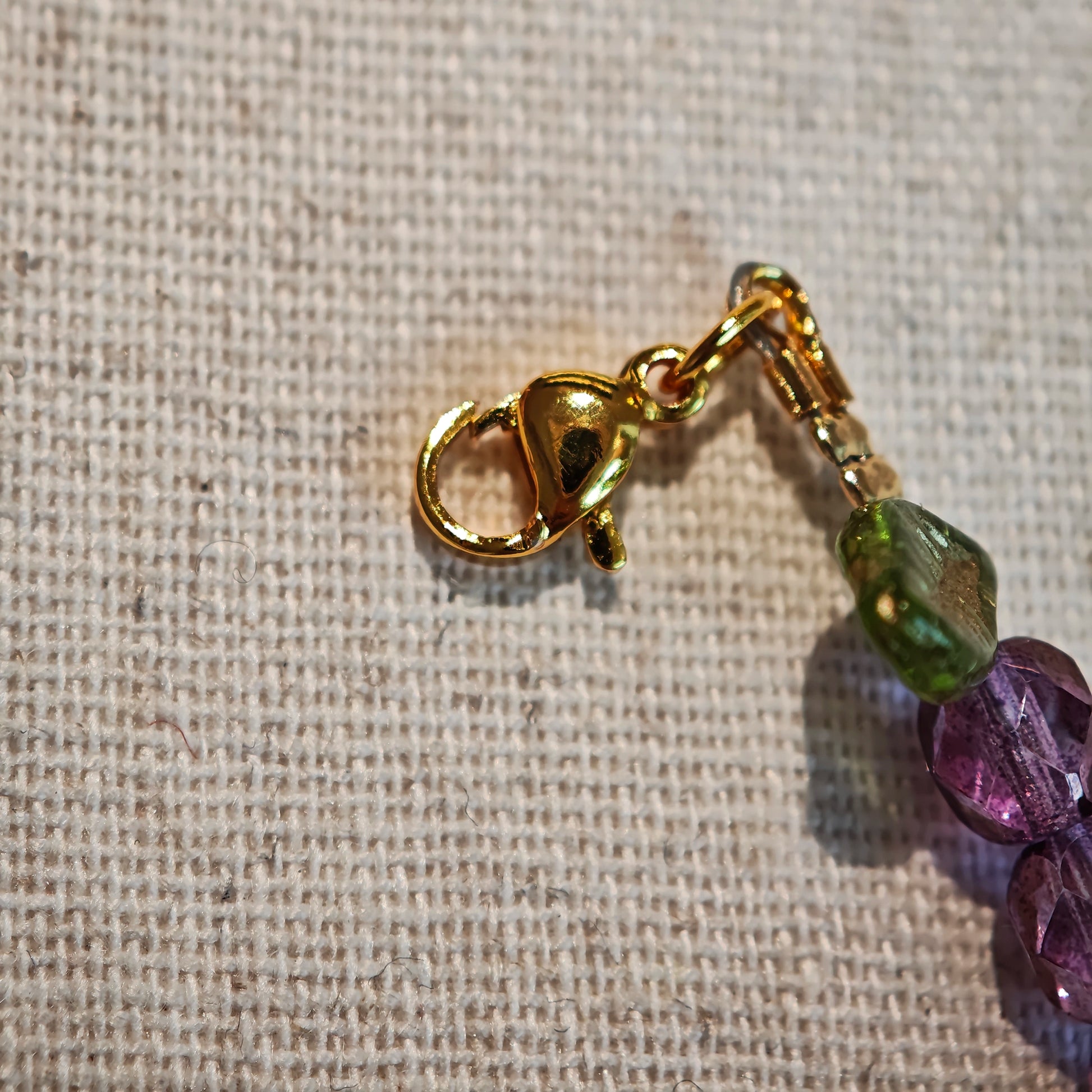 A purple hand-strung bracelet with luminous Czech glass beads & delicate botanical charms.