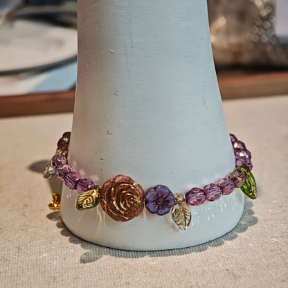 A purple hand-strung bracelet with luminous Czech glass beads & delicate botanical charms.