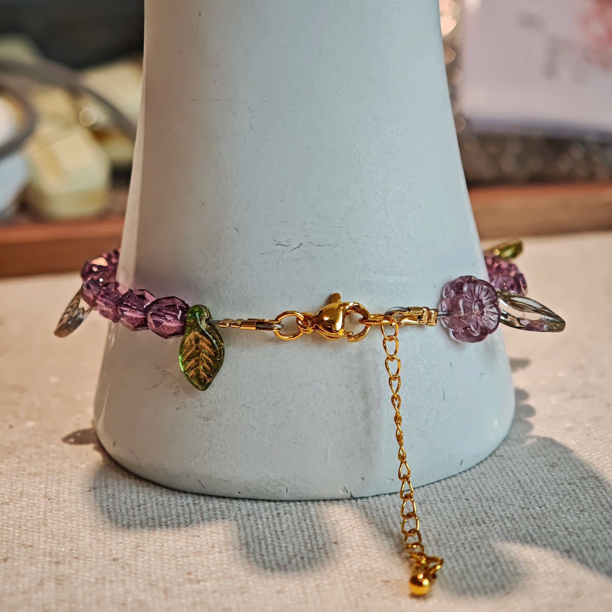 A purple hand-strung bracelet with luminous Czech glass beads & delicate botanical charms.