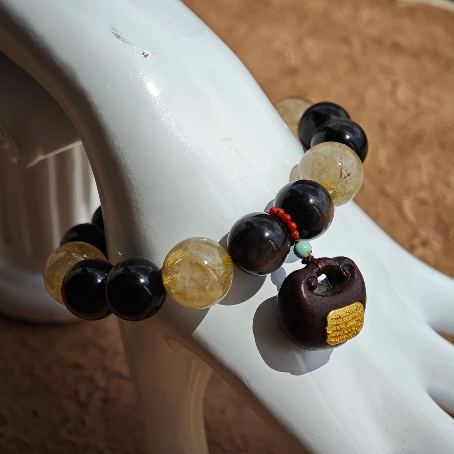 This is a silver sheen obsidian and rutilated quartz bracelet, finished with aloeswood and south red agate pendant—luxury forged in primal power.