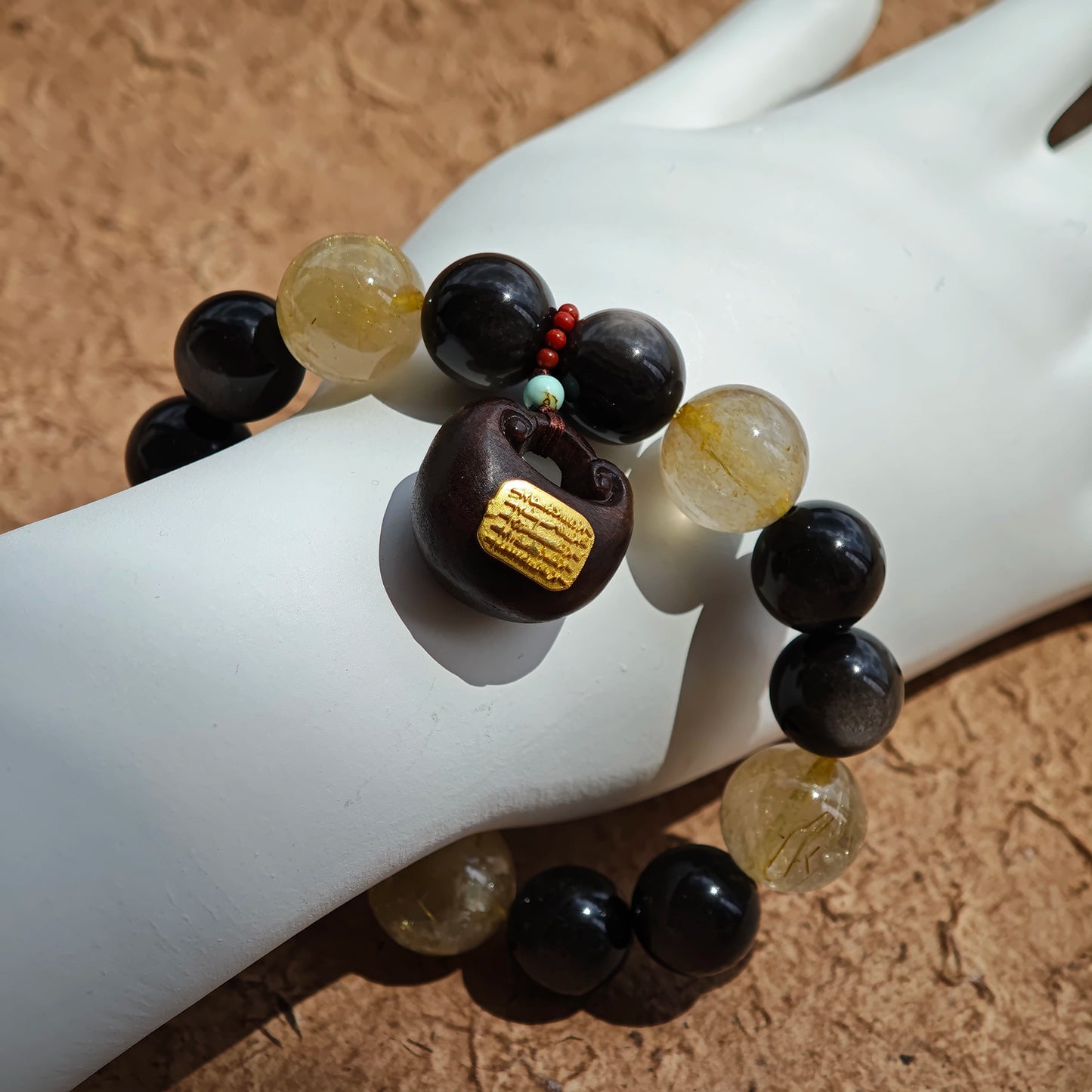 This is a silver sheen obsidian and rutilated quartz bracelet, finished with aloeswood and south red agate pendant—luxury forged in primal power.