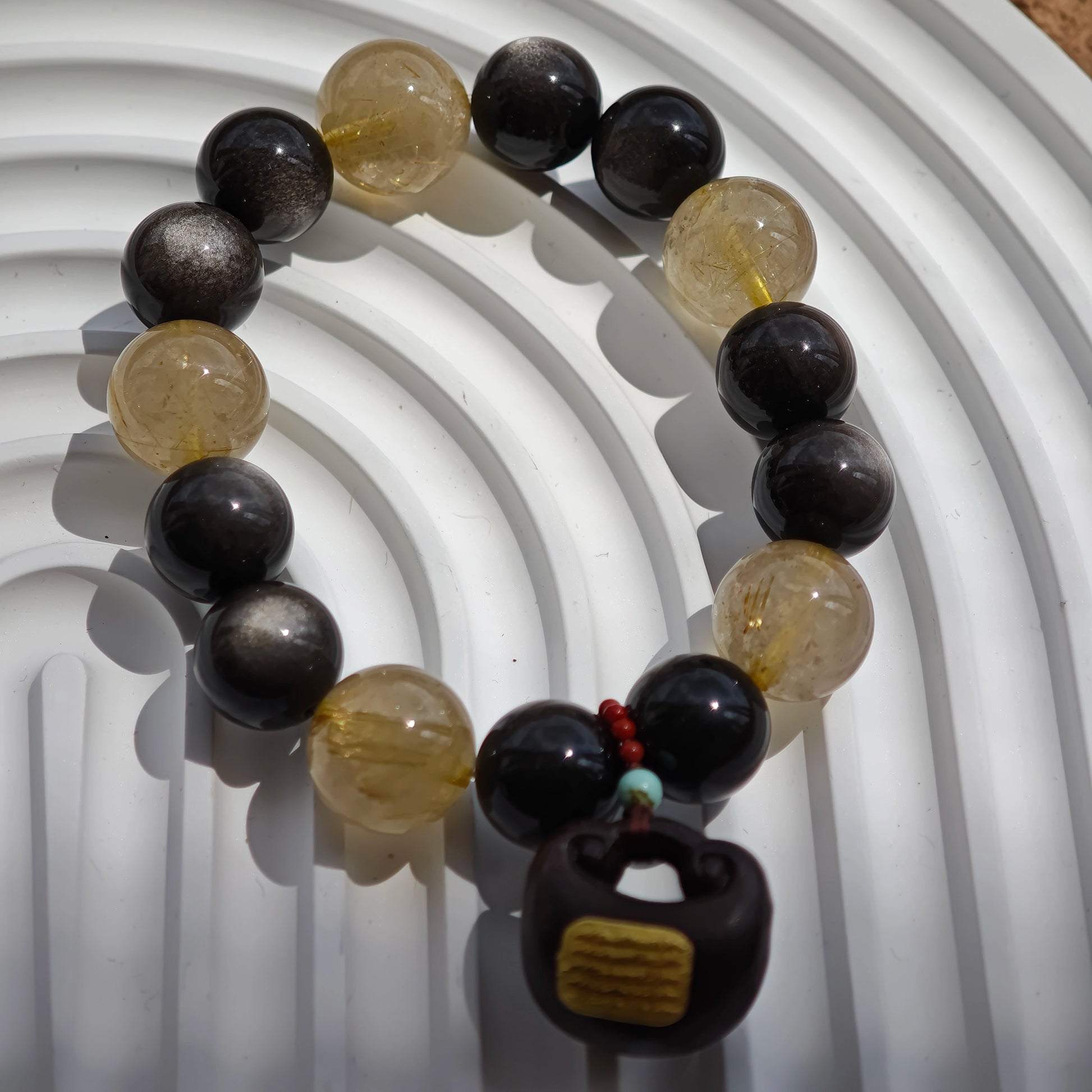 This is a silver sheen obsidian and rutilated quartz bracelet, finished with aloeswood and south red agate pendant—luxury forged in primal power.