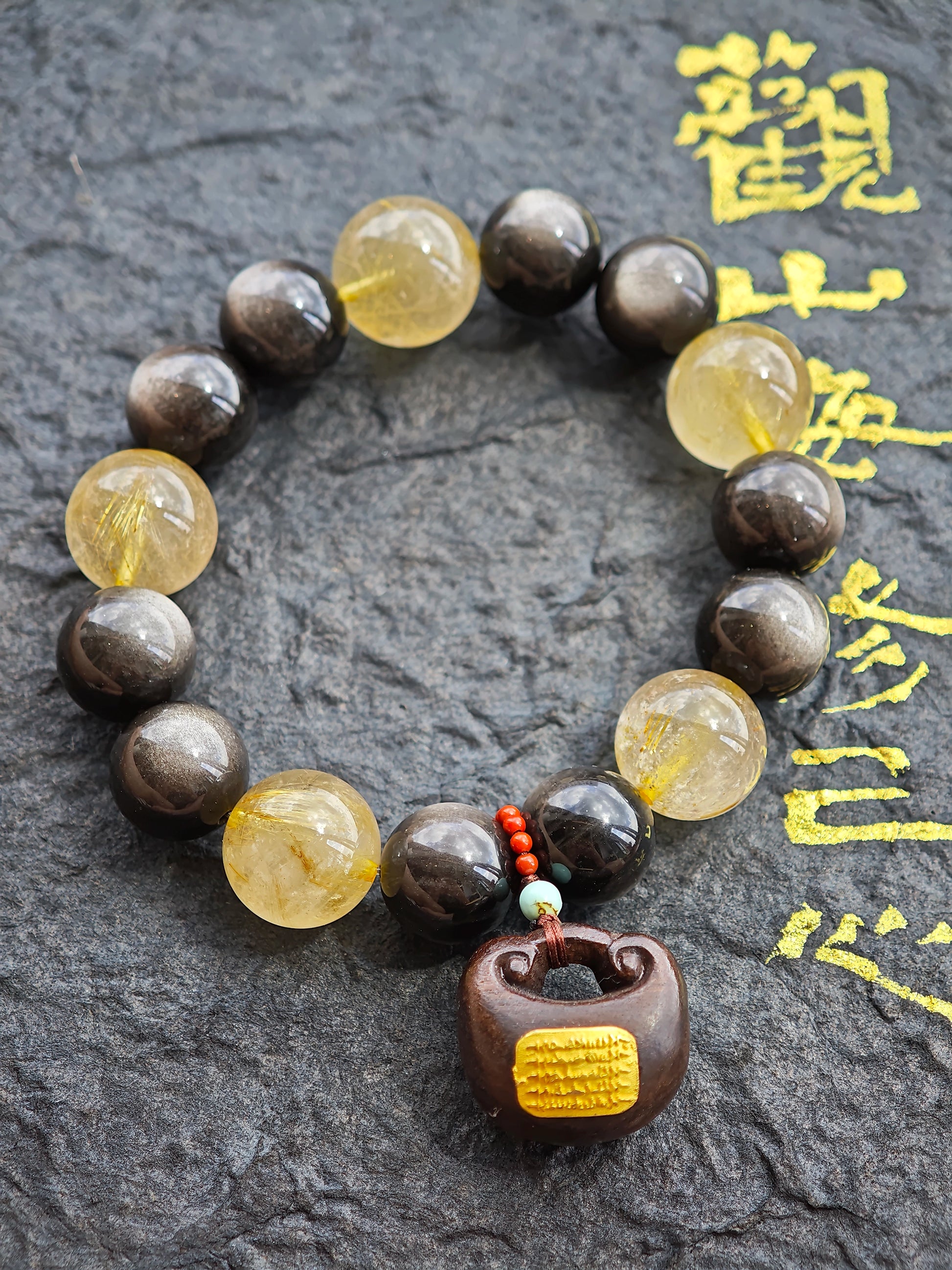 This is a silver sheen obsidian and rutilated quartz bracelet, finished with aloeswood and south red agate pendant—luxury forged in primal power.