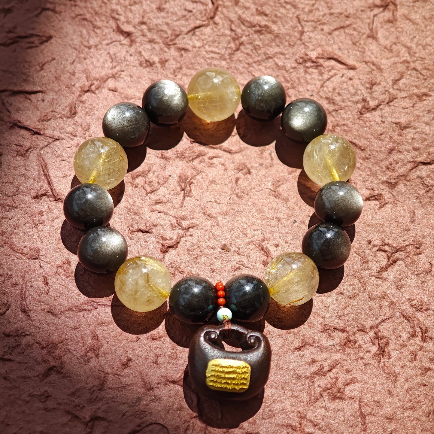 This is a silver sheen obsidian and rutilated quartz bracelet, finished with aloeswood and south red agate pendant—luxury forged in primal power.