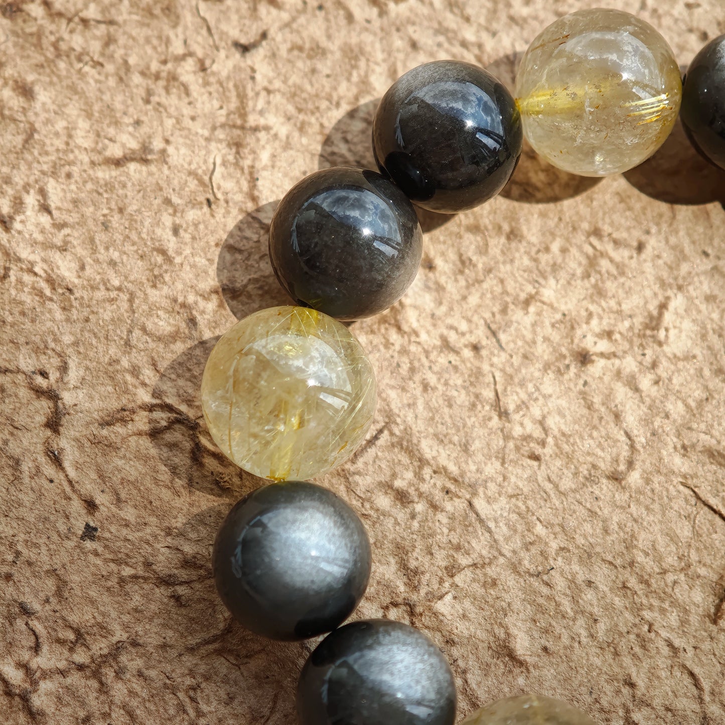 This is a silver sheen obsidian and rutilated quartz bracelet, finished with aloeswood and south red agate pendant—luxury forged in primal power.