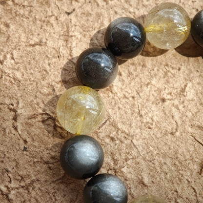 This is a silver sheen obsidian and rutilated quartz bracelet, finished with aloeswood and south red agate pendant—luxury forged in primal power.
