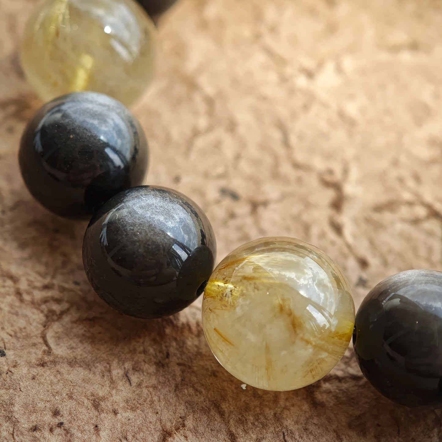 This is a silver sheen obsidian and rutilated quartz bracelet, finished with aloeswood and south red agate pendant—luxury forged in primal power.