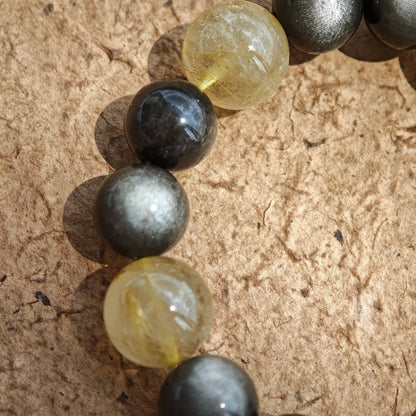 This is a silver sheen obsidian and rutilated quartz bracelet, finished with aloeswood and south red agate pendant—luxury forged in primal power.