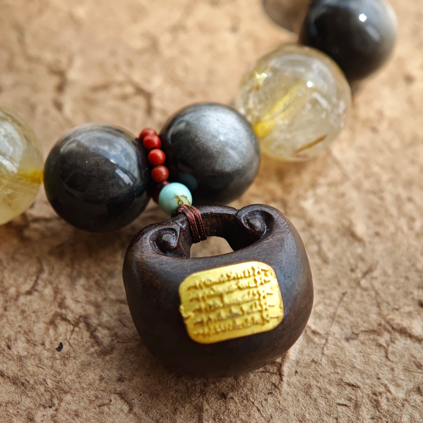 This is a silver sheen obsidian and rutilated quartz bracelet, finished with aloeswood and south red agate pendant—luxury forged in primal power.