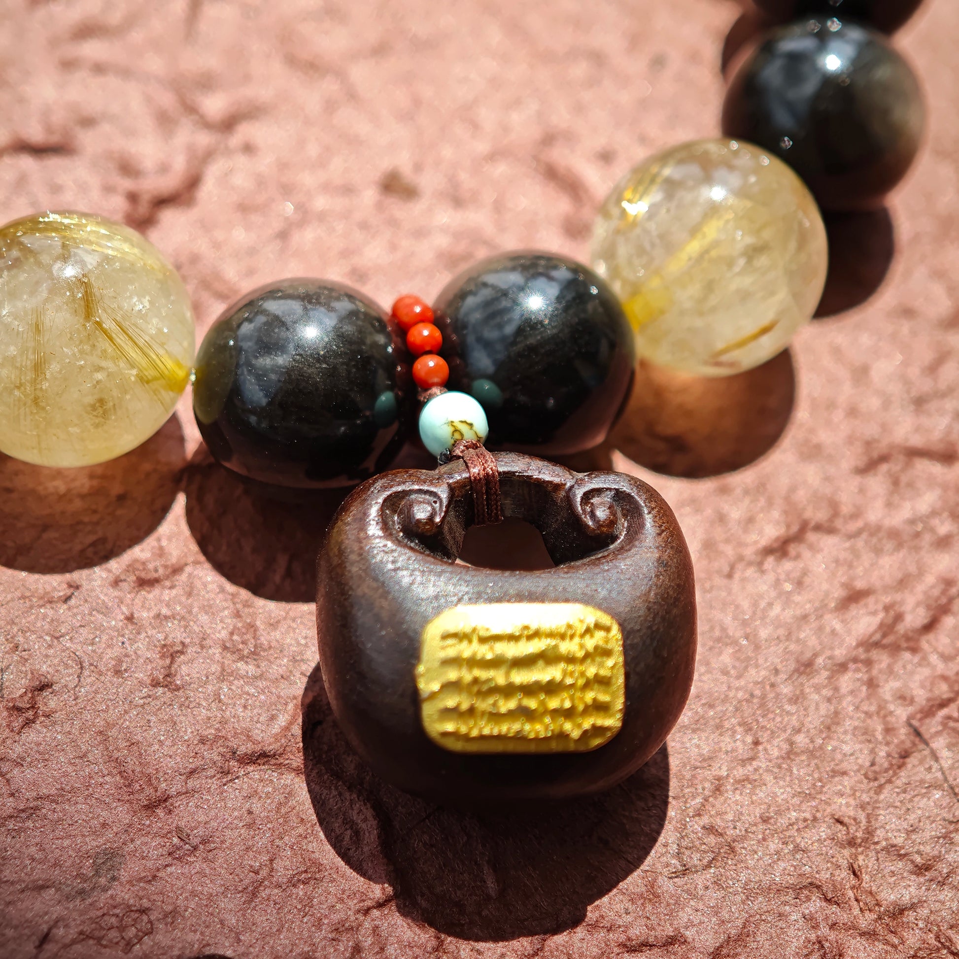 This is a silver sheen obsidian and rutilated quartz bracelet, finished with aloeswood and south red agate pendant—luxury forged in primal power.