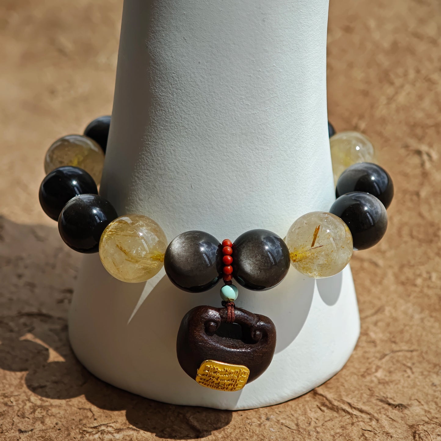 This is a silver sheen obsidian and rutilated quartz bracelet, finished with aloeswood and south red agate pendant—luxury forged in primal power.