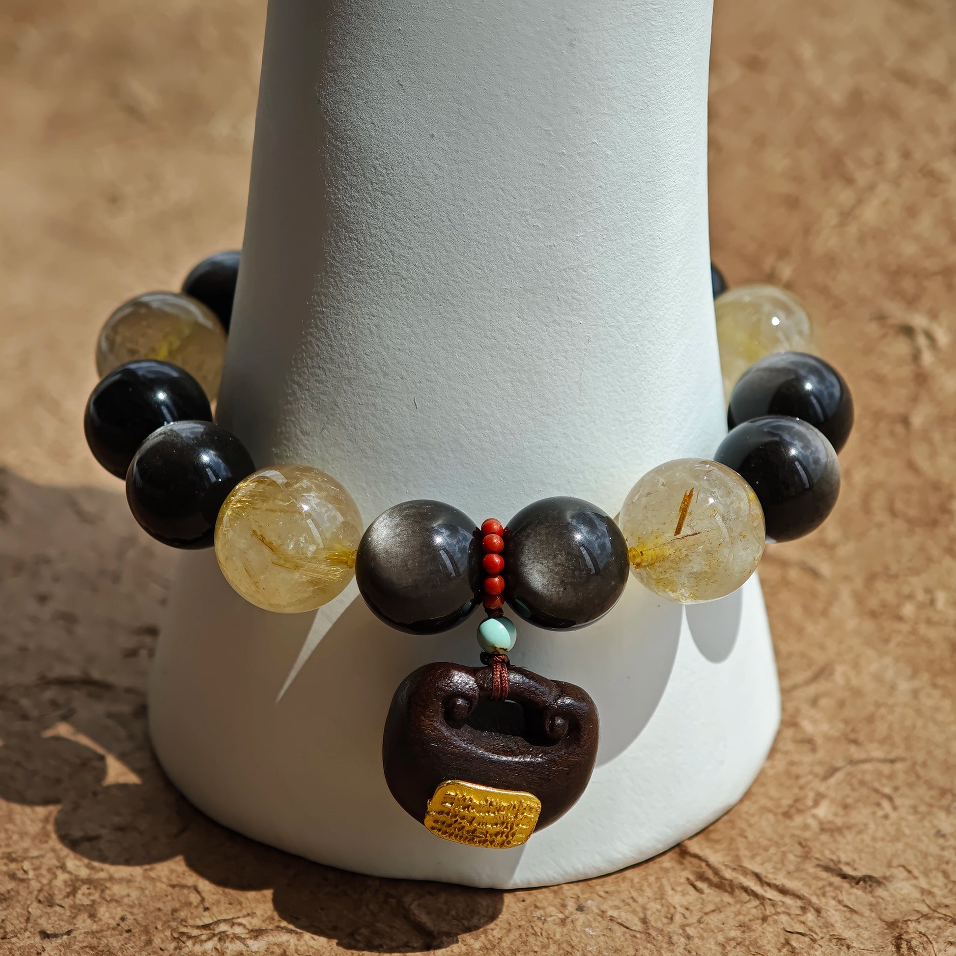 This is a silver sheen obsidian and rutilated quartz bracelet, finished with aloeswood and south red agate pendant—luxury forged in primal power.