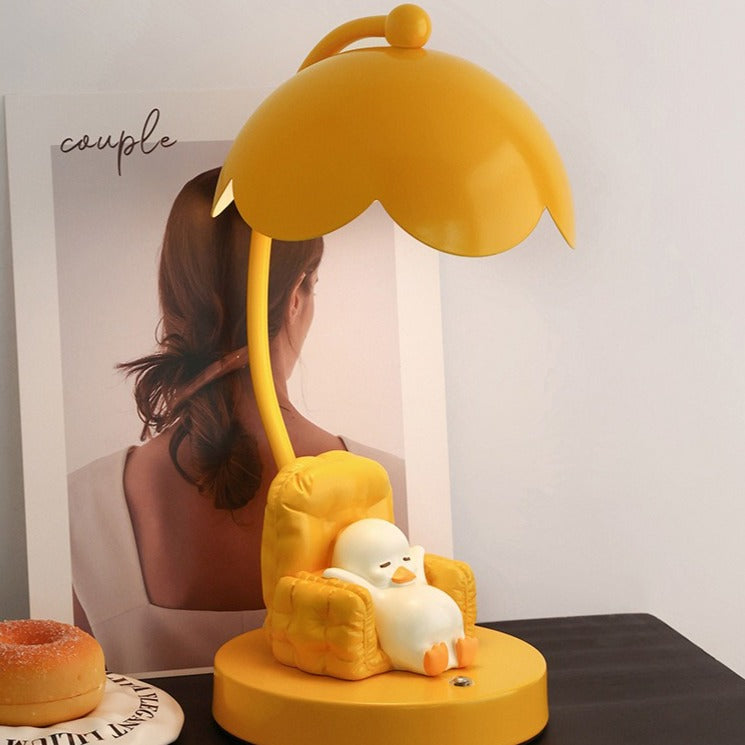 This is a bedside lamp with a design of a duck lying in a yellow sofa. And it comes with a round lampshade. Smooth rounded lines and artistic detailing make it a decorative bedside lamp and a comforting companion after long workdays.