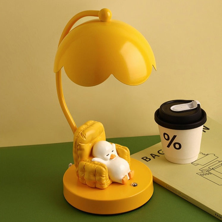 This is a bedside lamp with a design of a duck lying in a yellow sofa. And it comes with a round lampshade. Smooth rounded lines and artistic detailing make it a decorative bedside lamp and a comforting companion after long workdays.