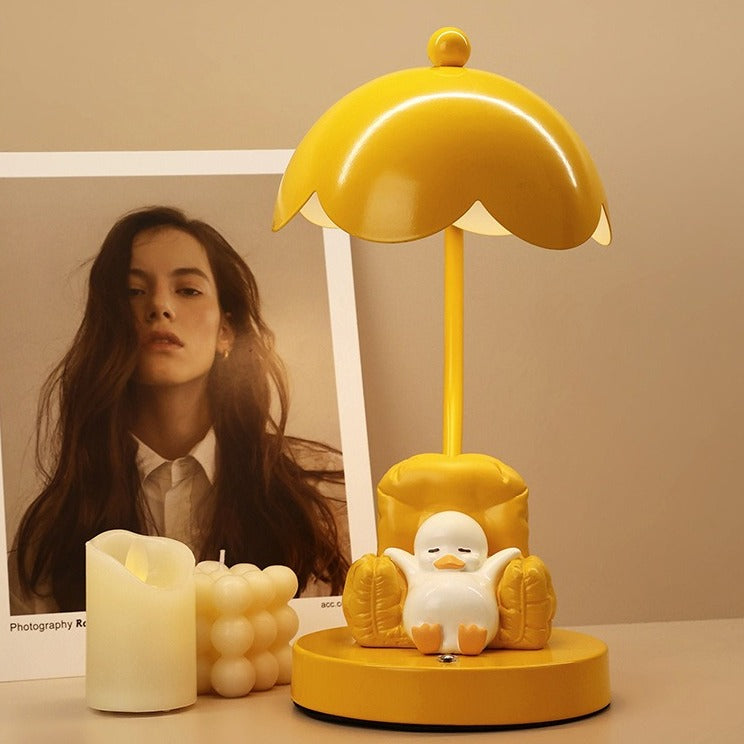 This is a bedside lamp with a design of a duck lying in a yellow sofa. And it comes with a round lampshade. Smooth rounded lines and artistic detailing make it a decorative bedside lamp and a comforting companion after long workdays.