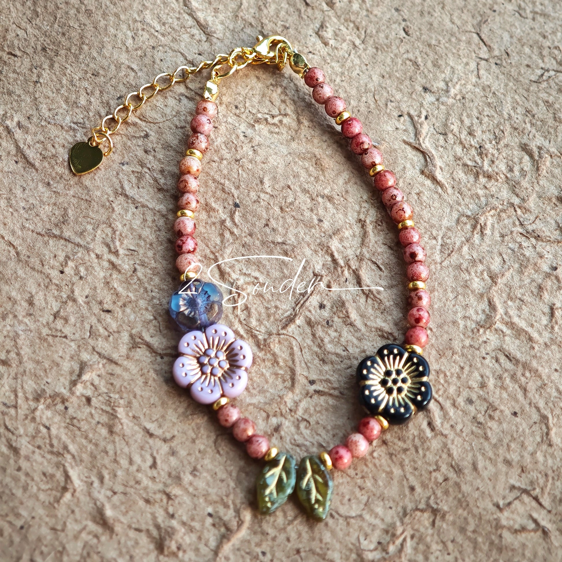 This is a bracelet that made of Czech beads. And it's highlighted by blue, purple, and black flower charms and green leaf accents, creating a stunningly attractive design.