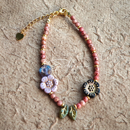 This is a bracelet that made of Czech beads. And it's highlighted by blue, purple, and black flower charms and green leaf accents, creating a stunningly attractive design.