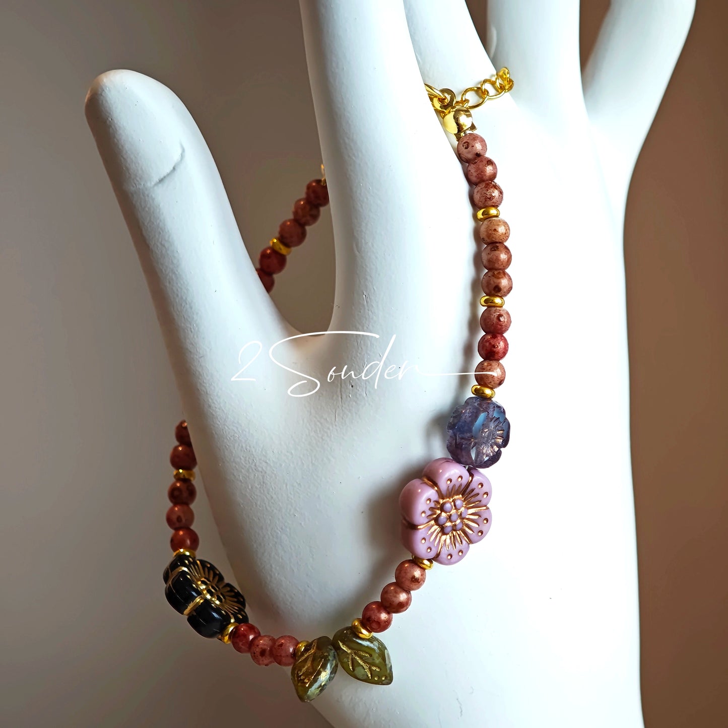 This is a bracelet that made of Czech beads. And it's highlighted by blue, purple, and black flower charms and green leaf accents, creating a stunningly attractive design.