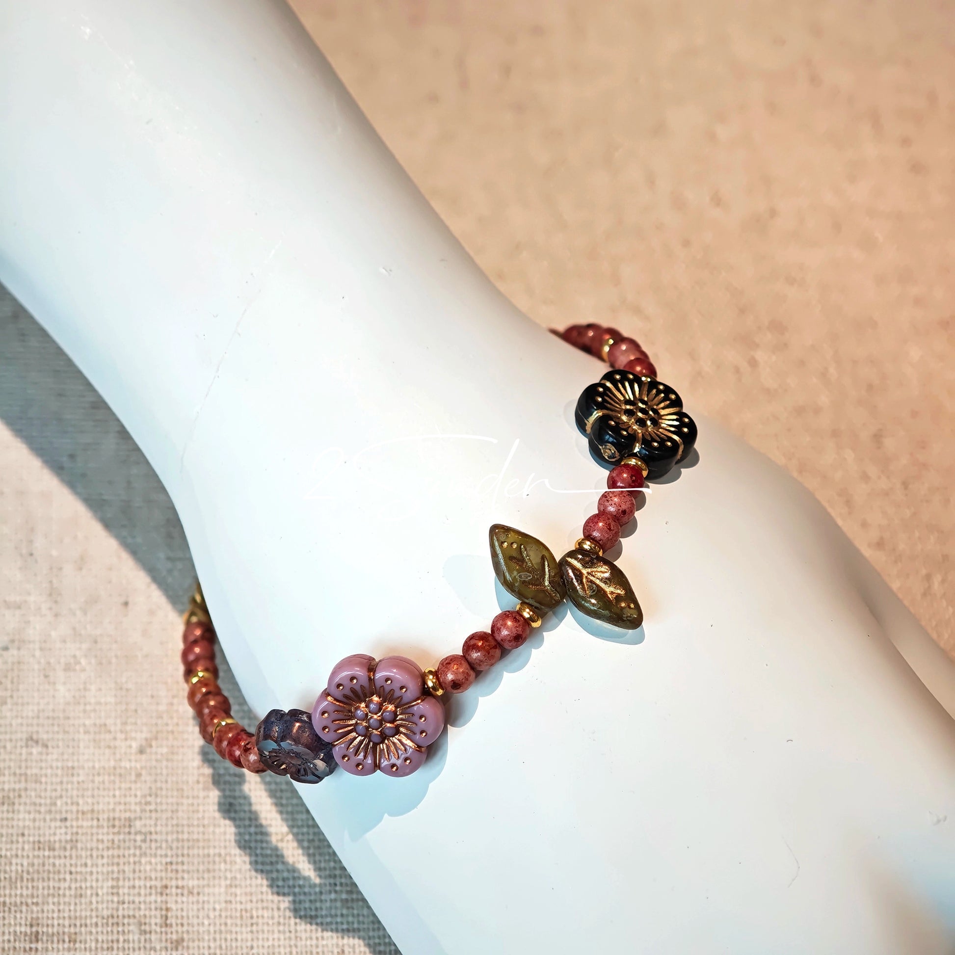 This is a bracelet that made of Czech beads. And it's highlighted by blue, purple, and black flower charms and green leaf accents, creating a stunningly attractive design.