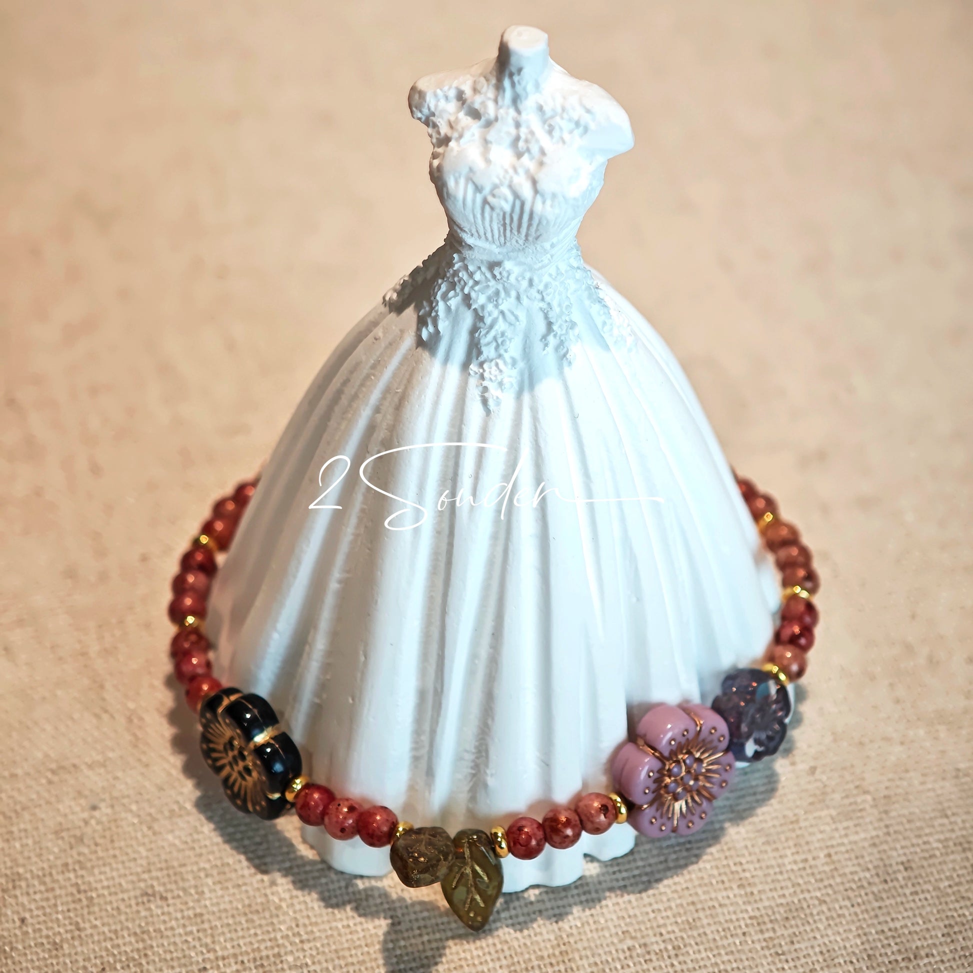 This is a bracelet that made of Czech beads. And it's highlighted by blue, purple, and black flower charms and green leaf accents, creating a stunningly attractive design.