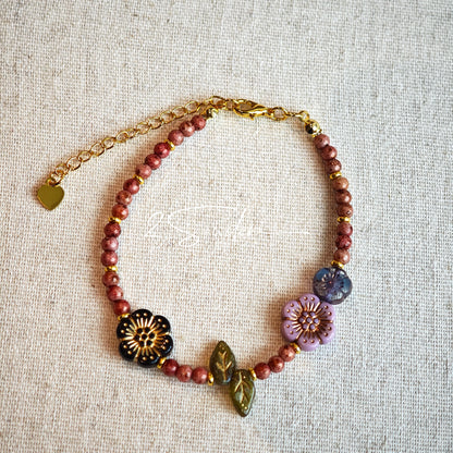 This is a bracelet that made of Czech beads. And it's highlighted by blue, purple, and black flower charms and green leaf accents, creating a stunningly attractive design.