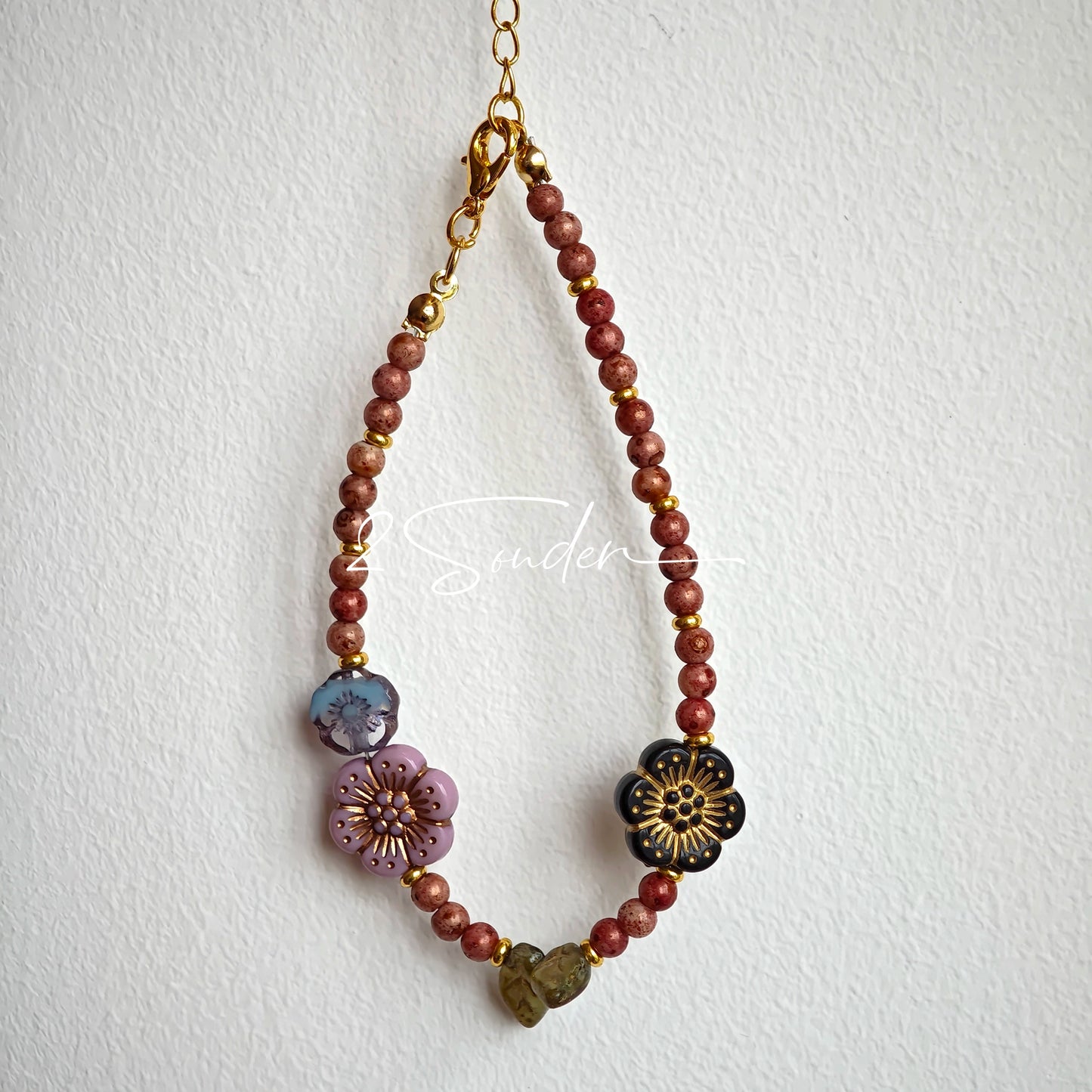 This is a bracelet that made of Czech beads. And it's highlighted by blue, purple, and black flower charms and green leaf accents, creating a stunningly attractive design.