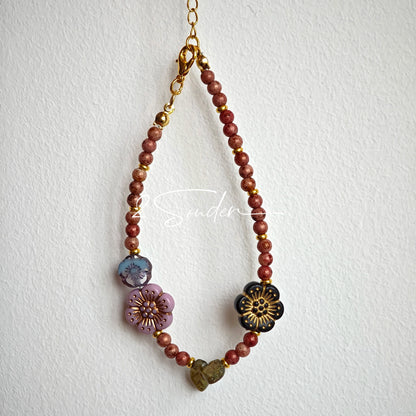 This is a bracelet that made of Czech beads. And it's highlighted by blue, purple, and black flower charms and green leaf accents, creating a stunningly attractive design.