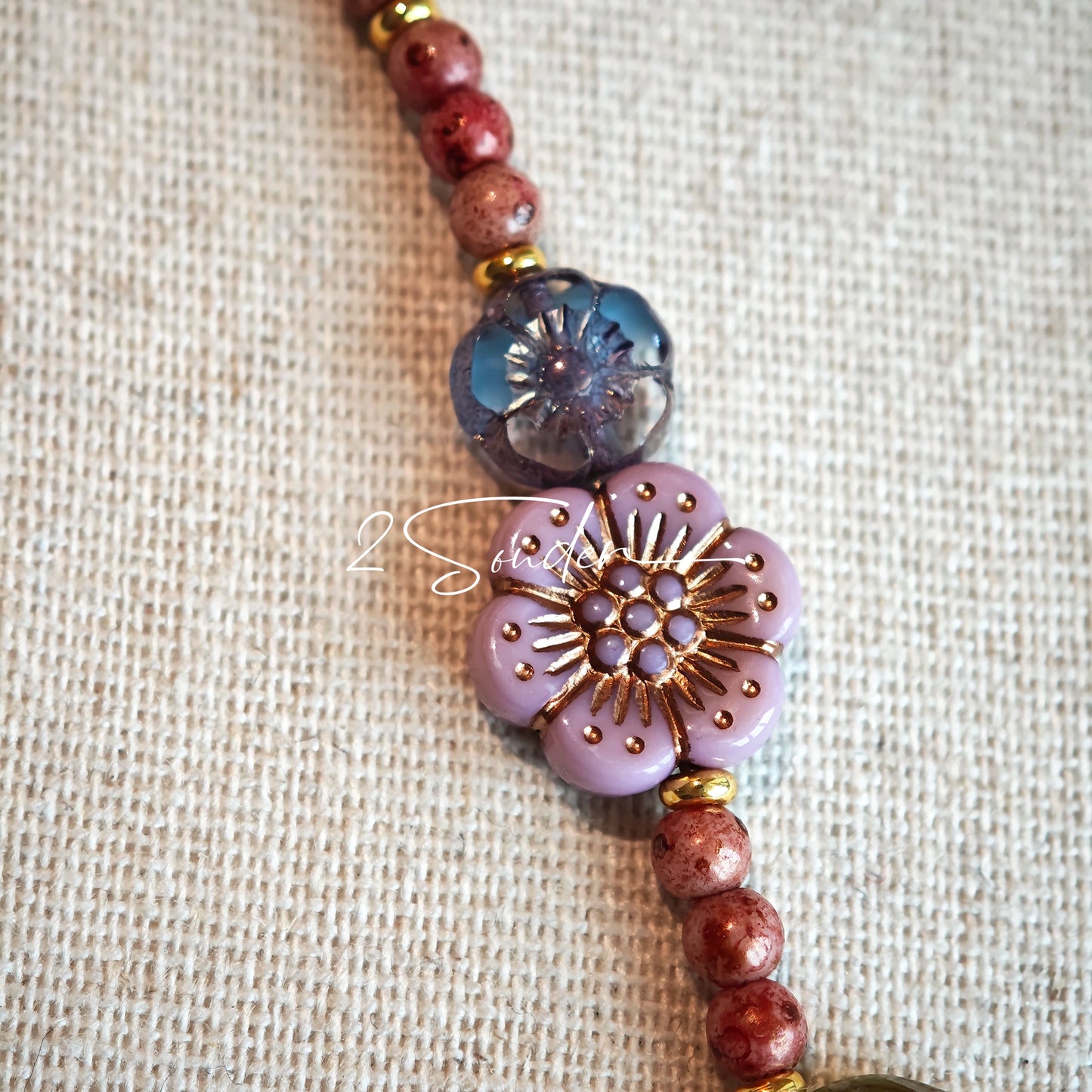 This is a bracelet that made of Czech beads. And it's highlighted by blue, purple, and black flower charms and green leaf accents, creating a stunningly attractive design.