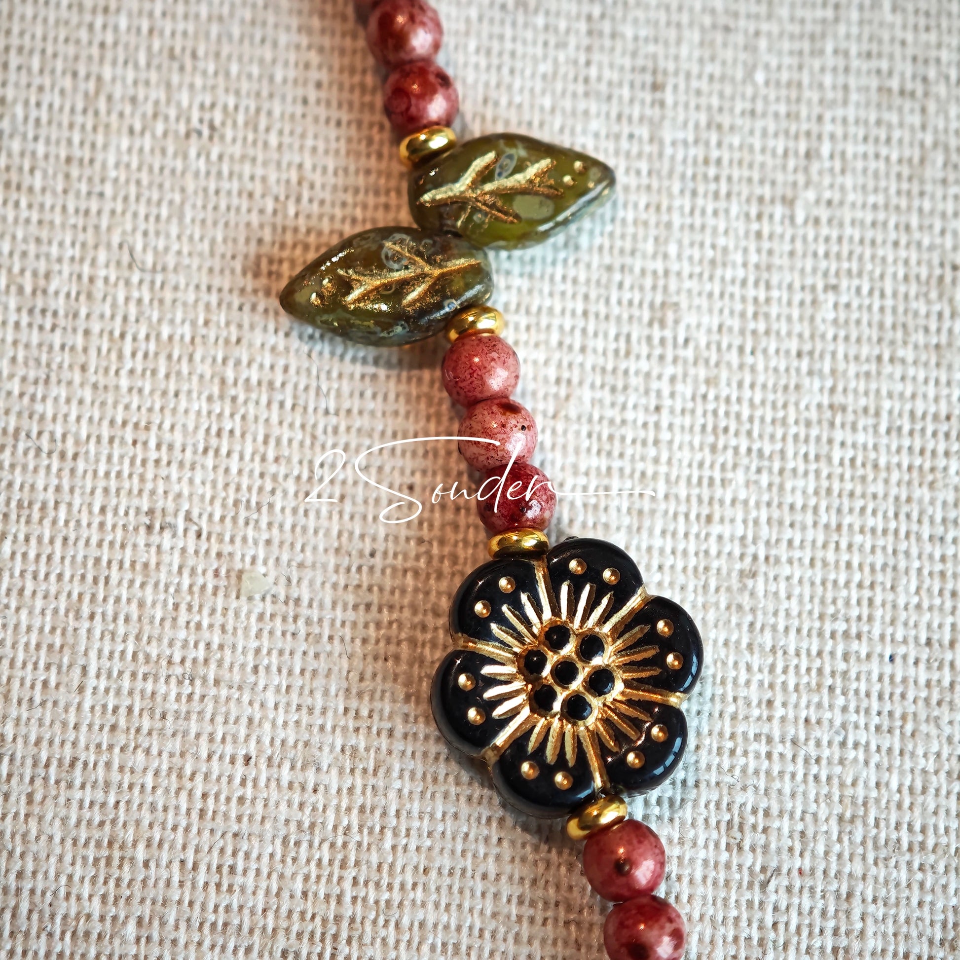 This is a bracelet that made of Czech beads. And it's highlighted by blue, purple, and black flower charms and green leaf accents, creating a stunningly attractive design.