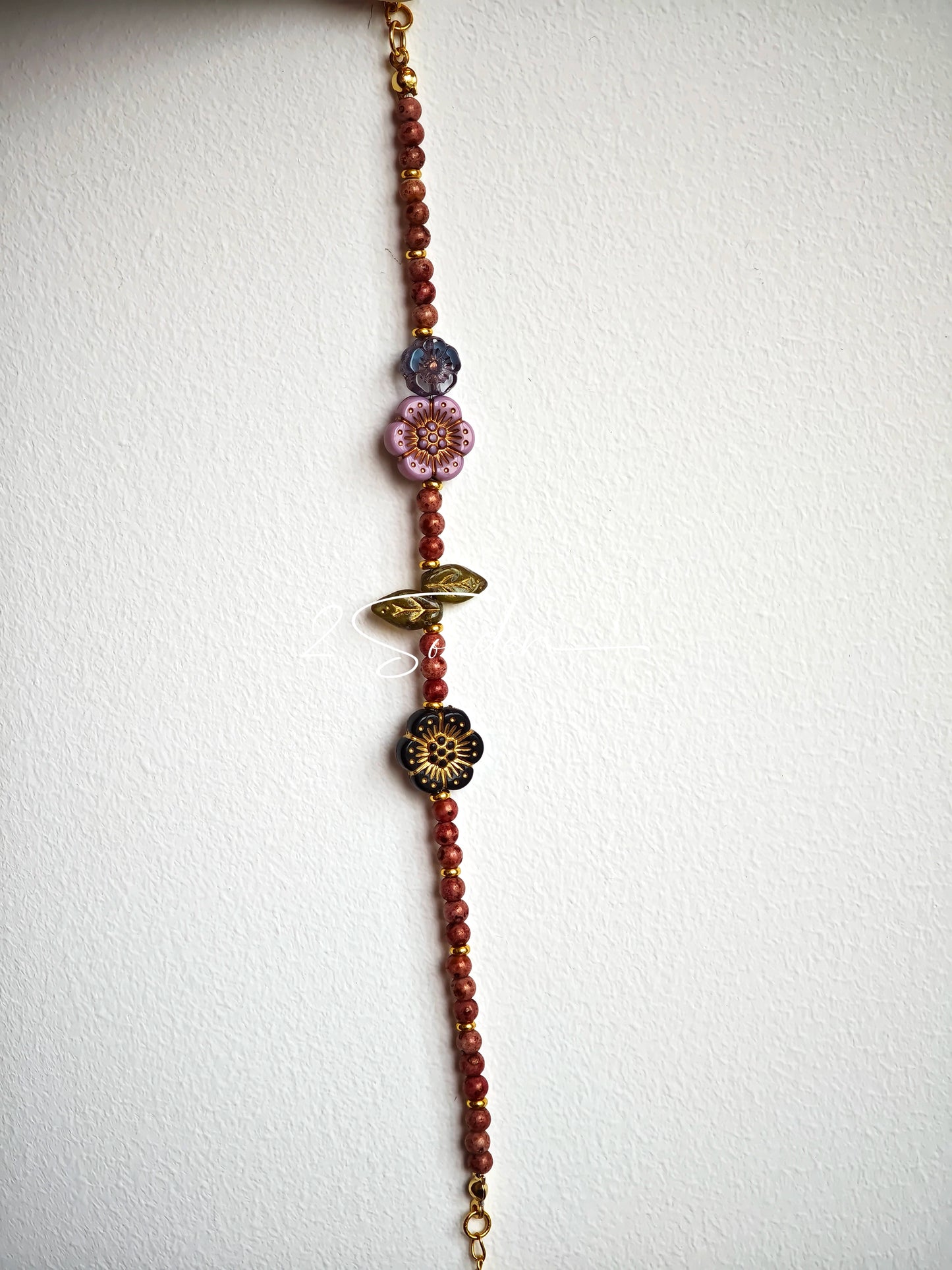 This is a bracelet that made of Czech beads. And it's highlighted by blue, purple, and black flower charms and green leaf accents, creating a stunningly attractive design.