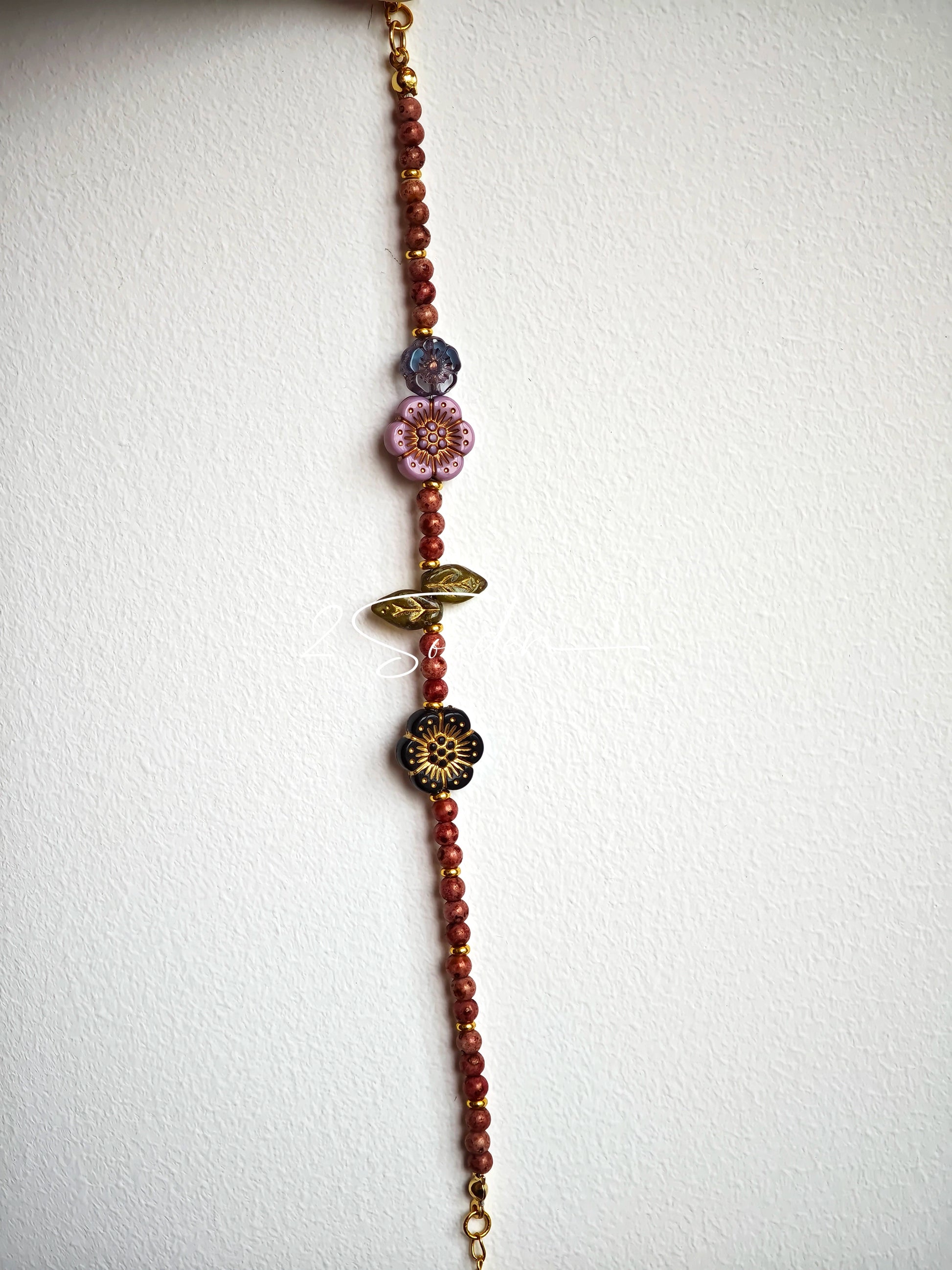 This is a bracelet that made of Czech beads. And it's highlighted by blue, purple, and black flower charms and green leaf accents, creating a stunningly attractive design.