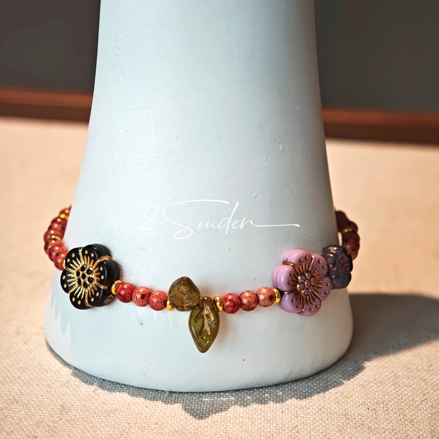 This is a bracelet that made of Czech beads. And it's highlighted by blue, purple, and black flower charms and green leaf accents, creating a stunningly attractive design.