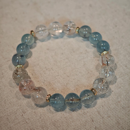 A cool aquamarine strand glows warmer with rutile and gold, mirroring a sunrise over water.