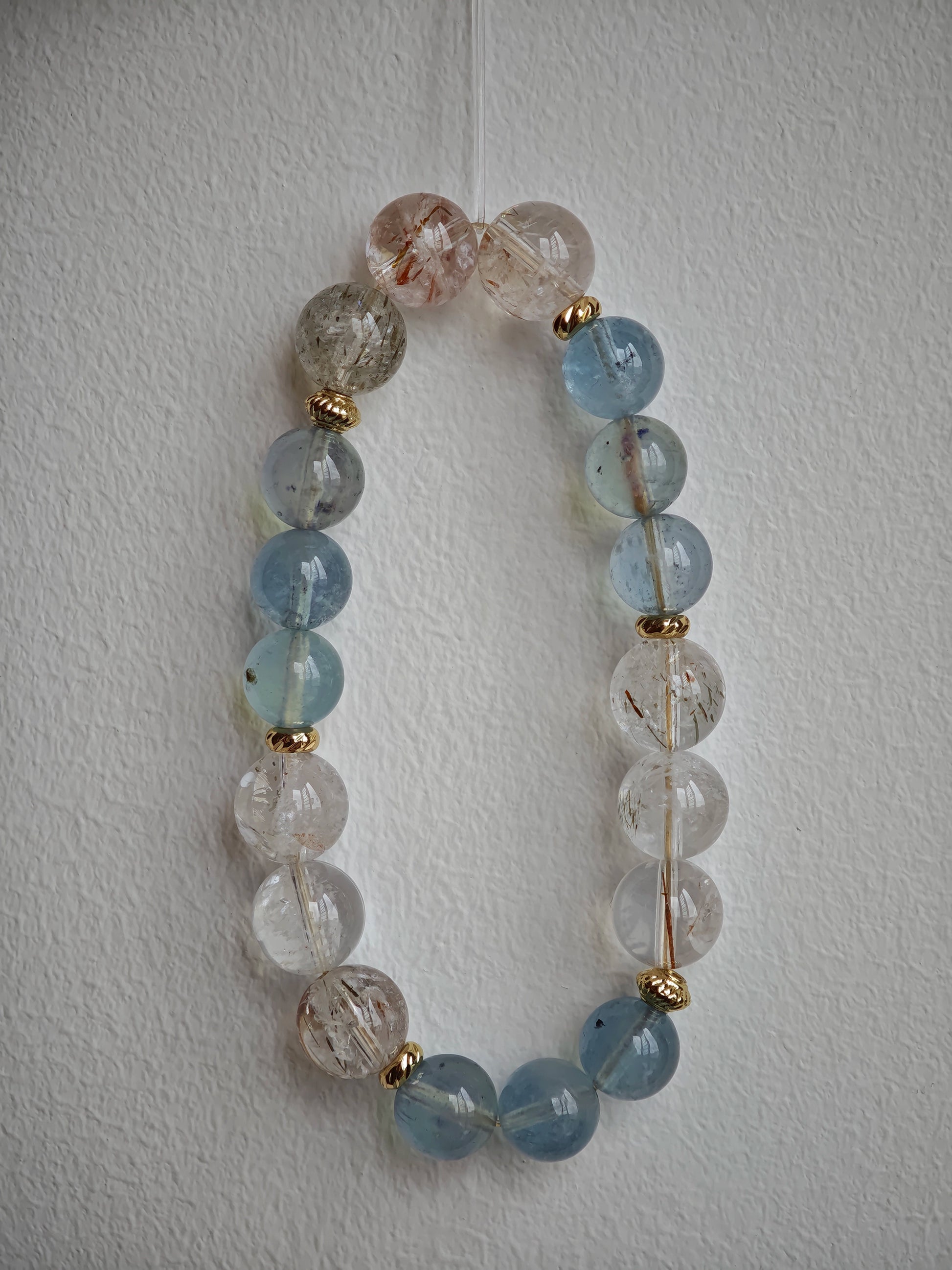 Aquamarine serenity and rutile brilliance dance between delicate gold beads.
