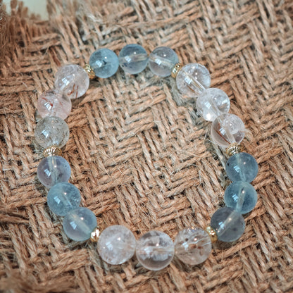 Gentle aquamarine and bright rutile bands are held by elegant gold spacers.