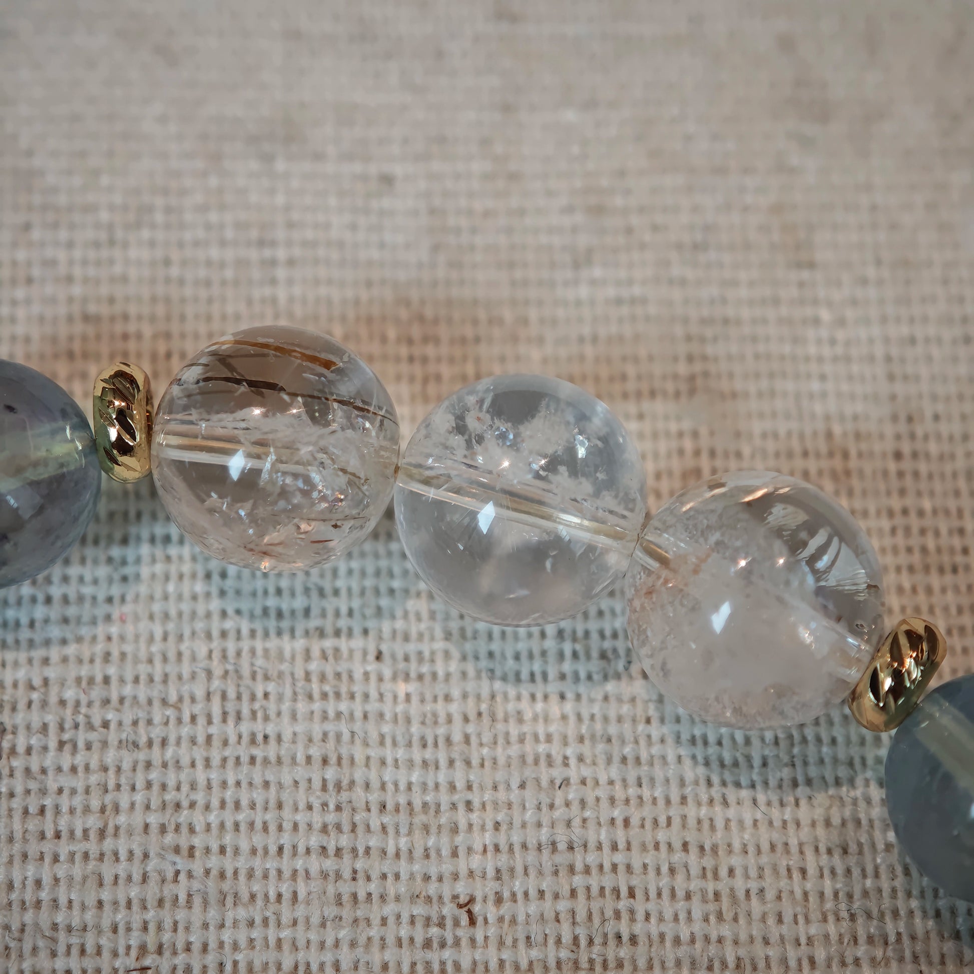 A strand of aquamarine and rutile glows between polished gold accents, echoing surf and sun.