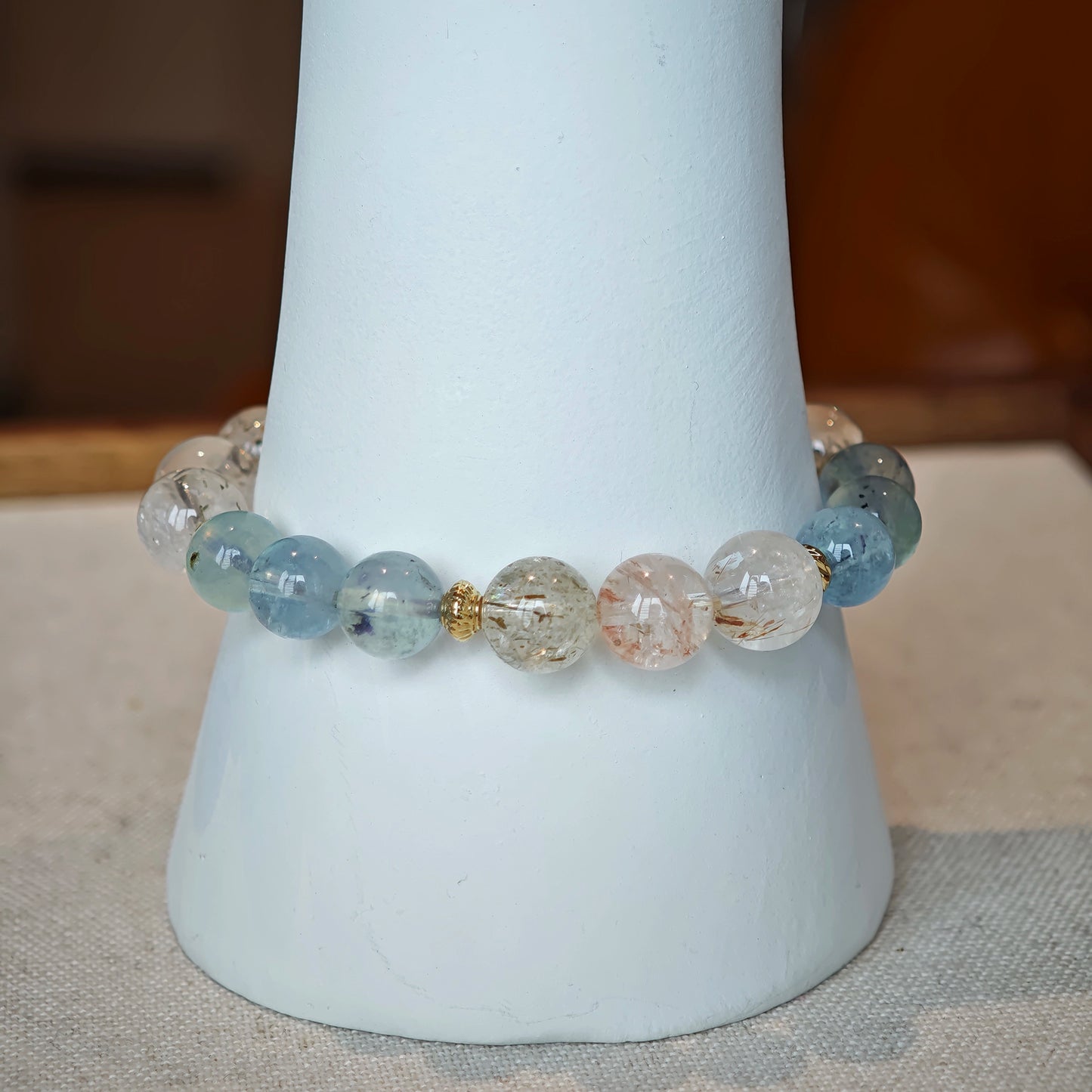 The bracelet braids tranquil ocean blue with golden needle sparks, framed in delicate gold.