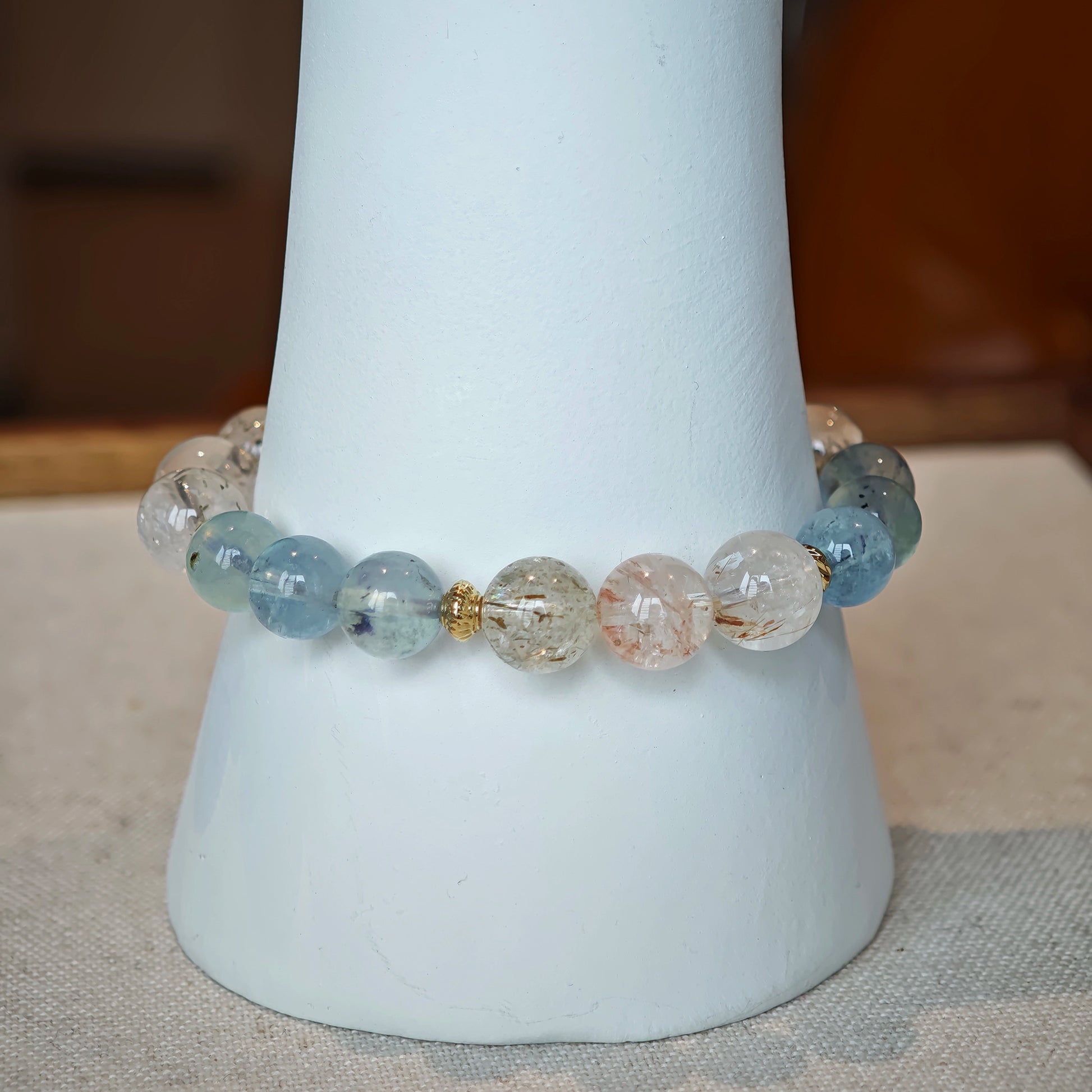 The bracelet braids tranquil ocean blue with golden needle sparks, framed in delicate gold.