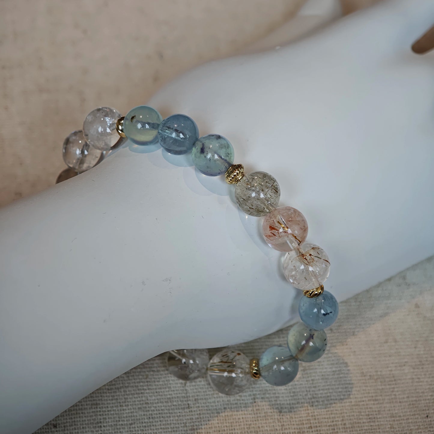 The bracelet layers marine aqua with golden rutile threads, all framed by gleaming gold.