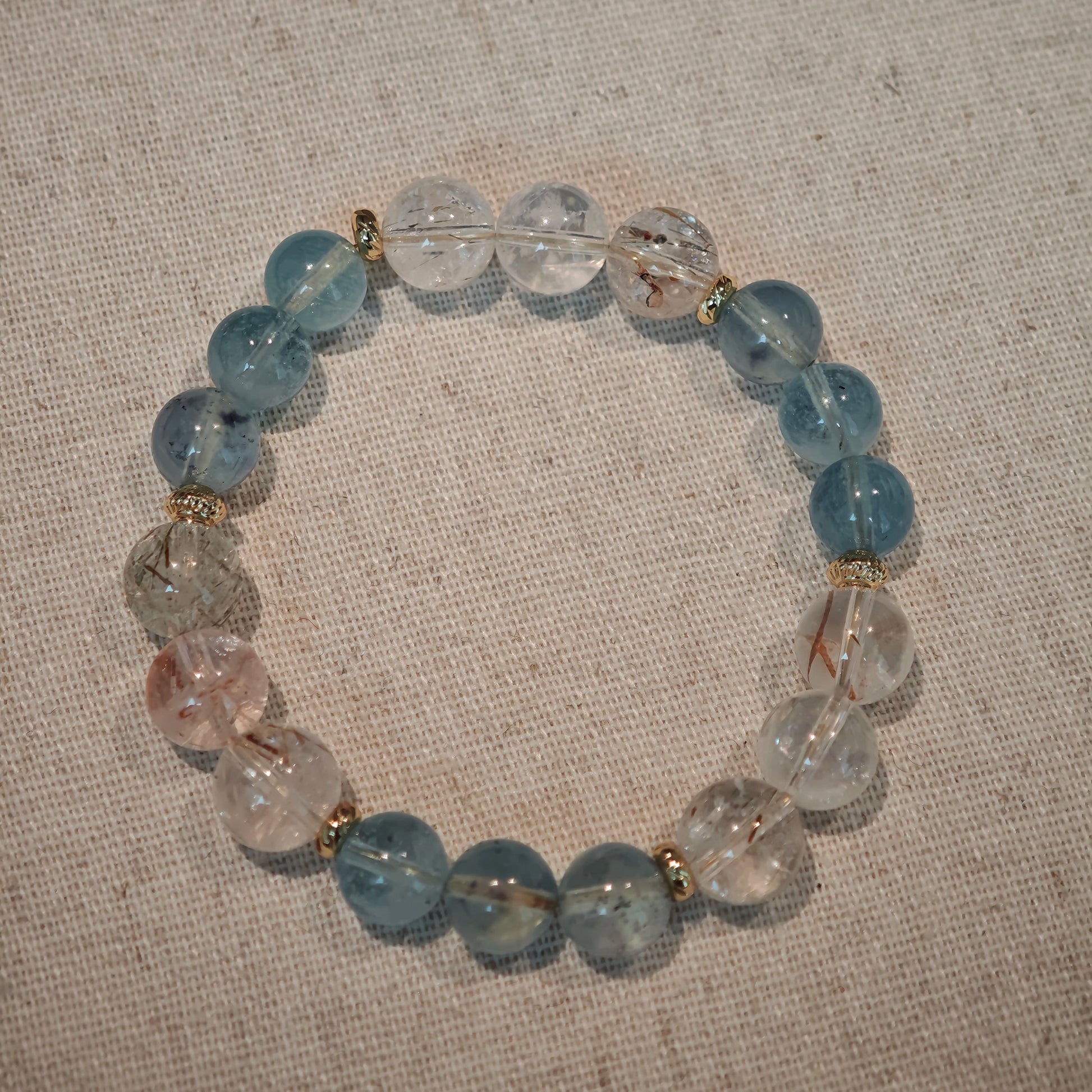 Soft aquamarine and radiant rutile flow through slender gold bridges, like dawn on the sea.