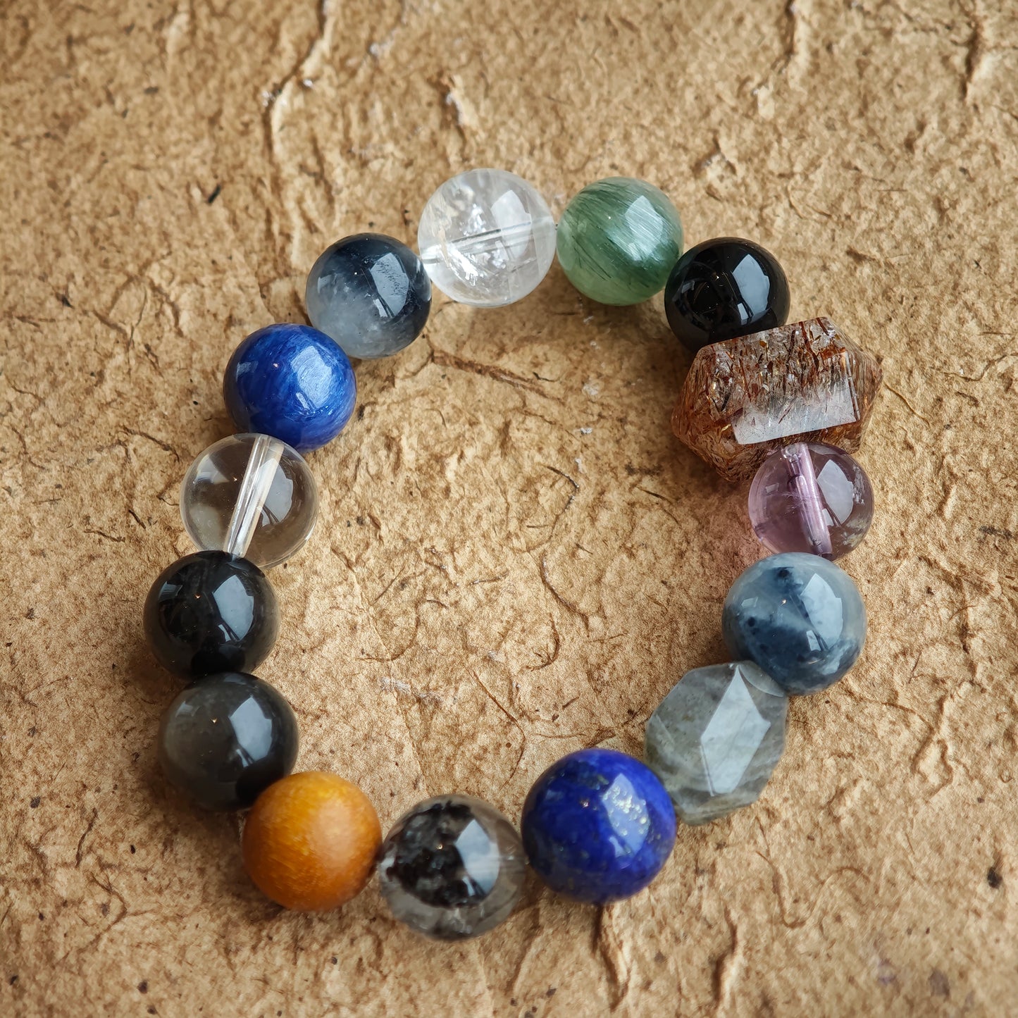 Deep slate and stormy ocean hues unite Black Gold Super Seven, Herkimer diamonds, clear quartz, sandalwood, amethyst, silver obsidian, white phantom, and kyanite on one strand.